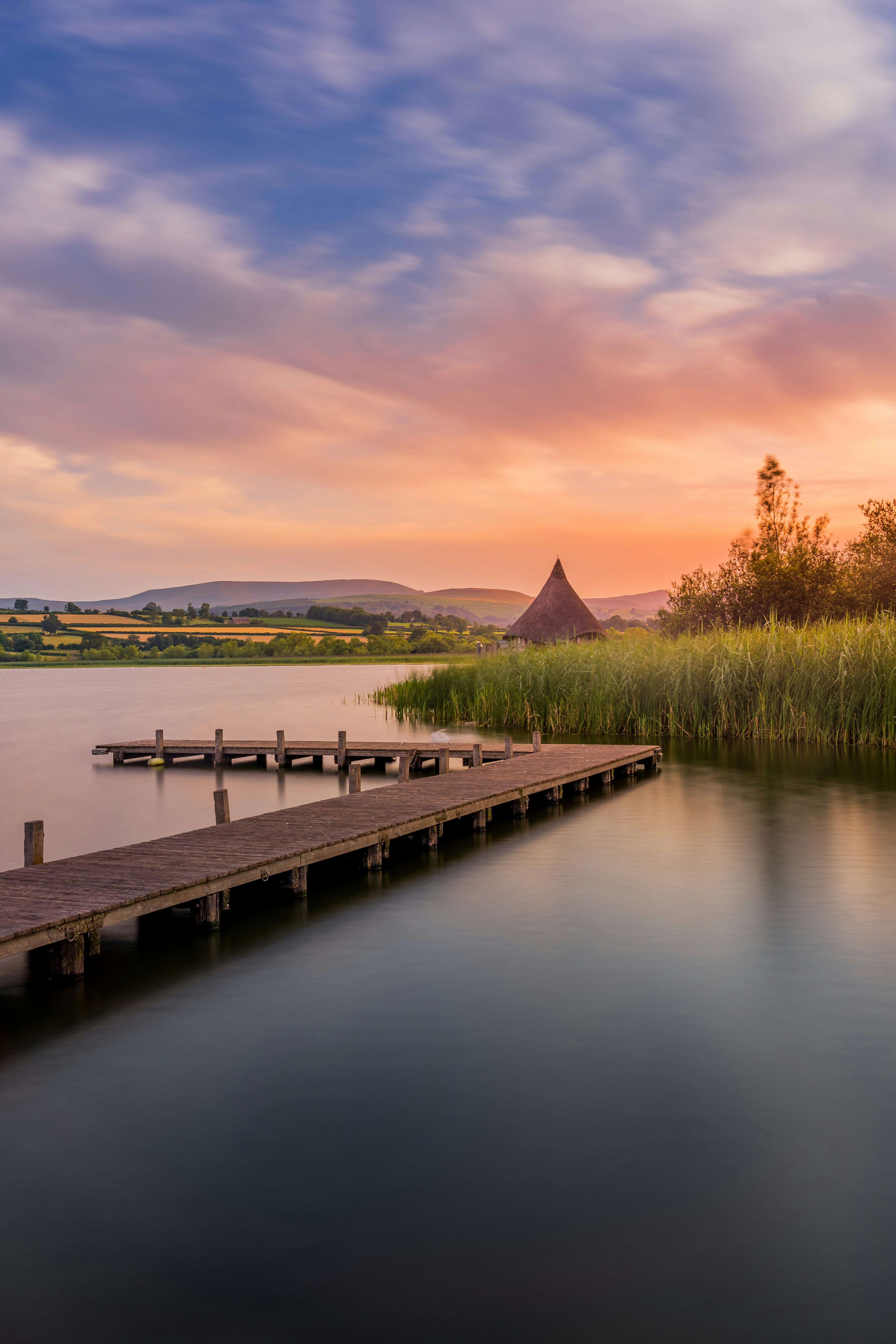 brown wooden dock on lake during sunset